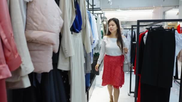 Mujer shopaholic elegir trajes en la tienda de moda — Vídeos de Stock