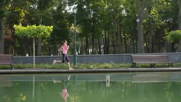 Mujer Cámara Lenta Corriendo Parque Cerca Del Estanque Reflejo Agua — Vídeo de stock