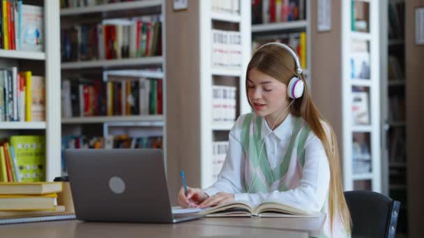 Vrouwelijke Student Zit Bibliotheek Huiswerk Maken Luisteren Naar Muziek Met — Stockvideo
