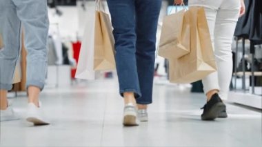 Farklı renkte kot pantolon giymiş kadın bacakları alışveriş merkezinde ağır çekimde yürüyor. Alışveriş torbası taşıyan kadınları takip ediyoruz. Arkadaşlar birlikte vakit geçiriyorlar. Alışveriş kavramı