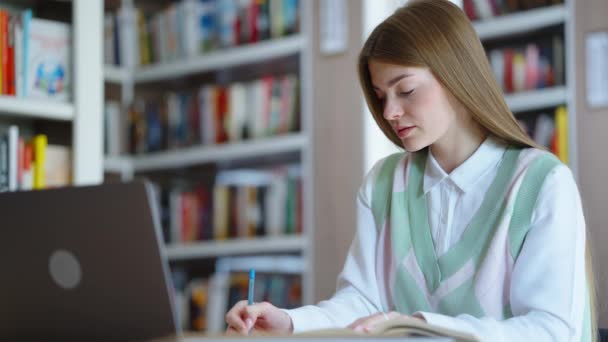 Estudiante haciendo deberes en la biblioteca — Vídeo de stock