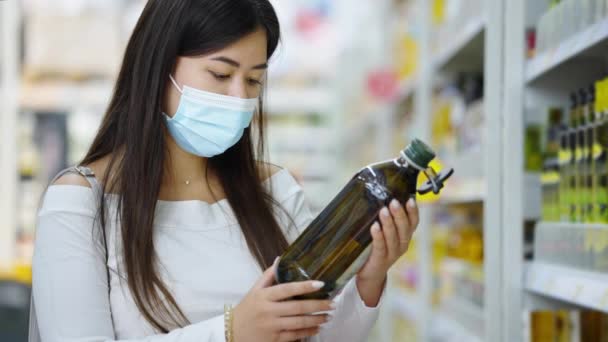 Mujer asiática revisando aceite de oliva en tienda — Vídeo de stock