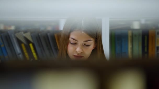 Жінка читає книгу на підлозі бібліотеки — стокове відео