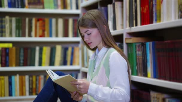 Женщина читает книгу на полу библиотеки — стоковое видео