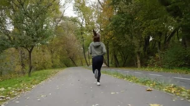 Donna sportiva che corre su strada con foglie cadute — Video Stock