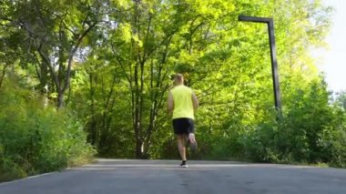 Güneşli bir sabahta parkta koşan bir adam