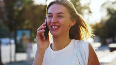 Caddede telefonla konuşan neşeli bir kadın.