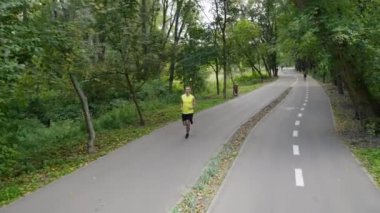 Bisiklet yolunun yakınındaki parkta koşan bir adam.