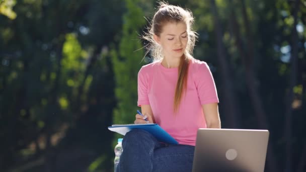 Étudiant utilisant un ordinateur portable pour étudier en ligne dans le parc — Video