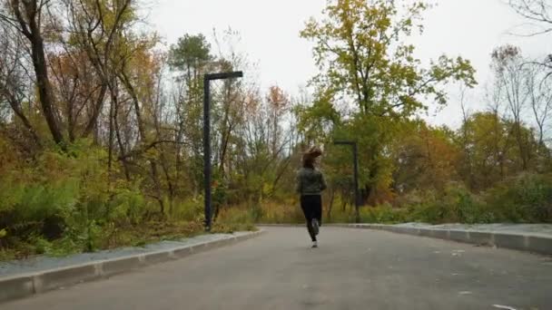 Frau joggt in Herbstpark in Straßenkurve — Stockvideo