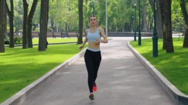 Piercingli bir kadın parkta ağır çekimde koşuyor.