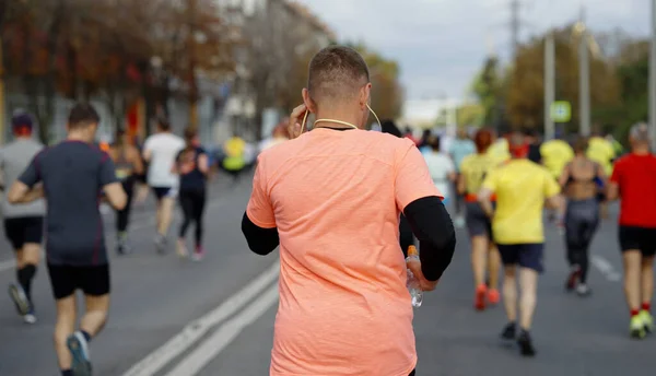 Man with earphones running marathon in city — Stock Photo, Image