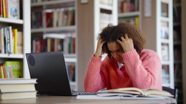 Chica afroamericana sufriendo dolor de cabeza en la biblioteca — Vídeo de stock