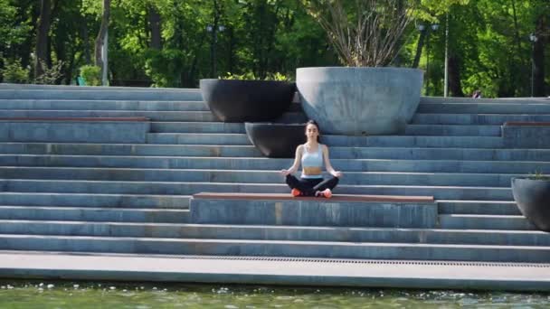 Женщина медитирует в позе йоги на лестнице в парке — стоковое видео