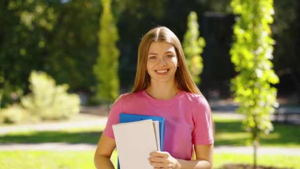 Γυναίκα φοιτήτρια με βιβλία στο χέρι στέκεται στο πάρκο — Αρχείο Βίντεο