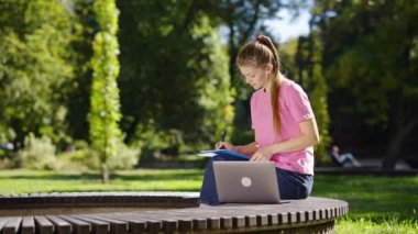Parkta çalışmak için dizüstü bilgisayar kullanan kız öğrenciler