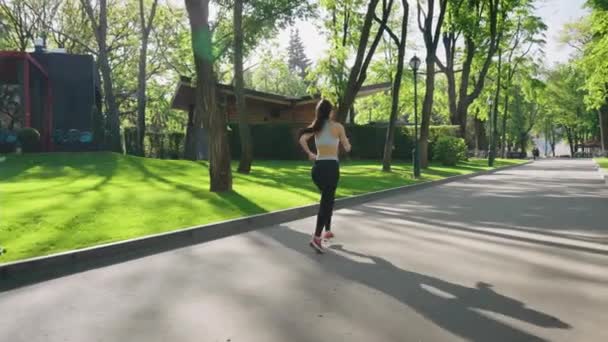 Slow motion vrouw joggen in park op zonnige ochtend — Stockvideo