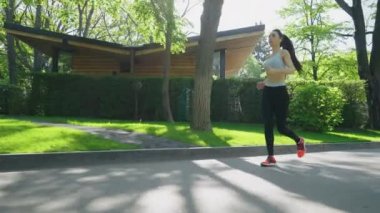 Güneşli bir günde parkta koşan bir kadın.