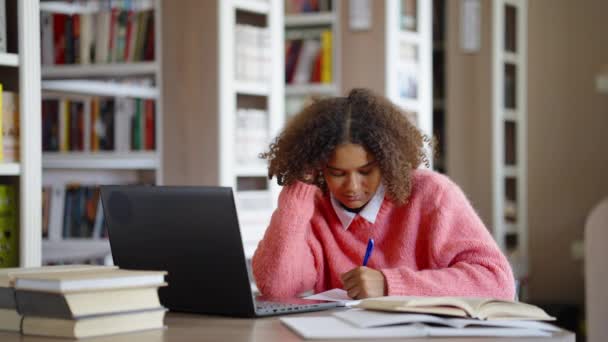 Afro-Amerikaans tienermeisje studeert in bibliotheek — Stockvideo