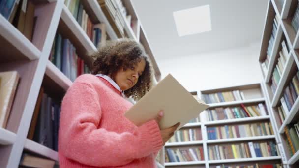 Afrikansk amerikansk flicka läser i biblioteket — Stockvideo