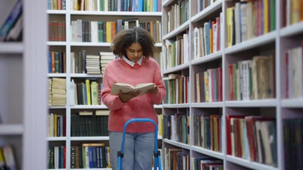 Afro-Amerikaanse tiener besteedt tijd in bibliotheek lezen — Stockvideo