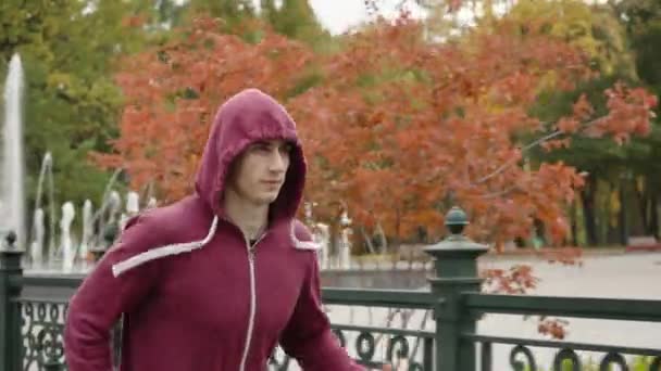 Mann mit Kapuze läuft in Herbstpark — Stockvideo