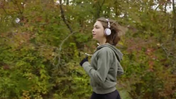 Adatto donna in auricolari che fanno jogging nella foresta — Video Stock