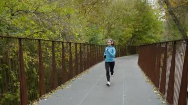 Parkta köprüde koşan kadın koşucu