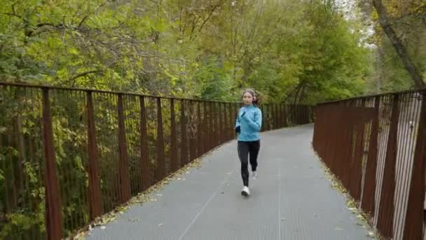 Бегунья бегает по мосту в парке — стоковое видео