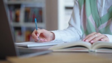 Kütüphanede ödev yapan öğrencilerin elleri