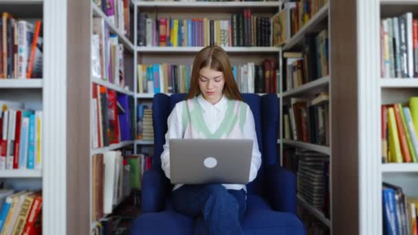 Estudiante sentado en la biblioteca y utilizando el ordenador portátil — Vídeo de stock