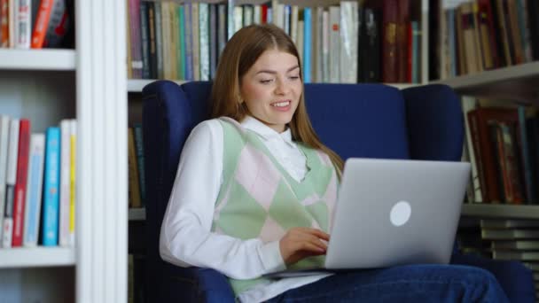 Женский видеочат с помощью ноутбука в библиотеке — стоковое видео