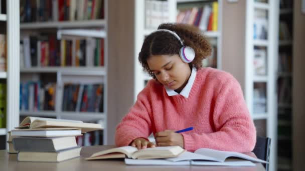 Kvinnlig student som gör läxor och lyssnar på musik — Stockvideo