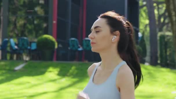 Slow motion vrouw met oortjes joggen in de ochtend — Stockvideo