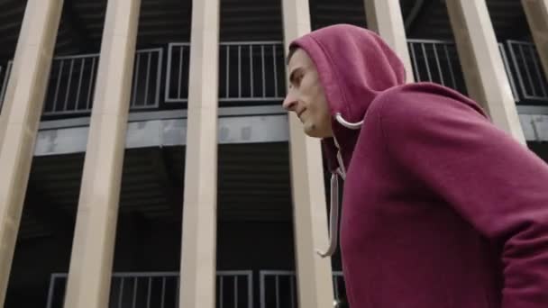 Jogger no capô correndo contra edifício moderno em câmera lenta — Vídeo de Stock