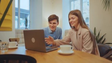 Kadın ve erkek kafede dizüstü bilgisayar izliyorlar.