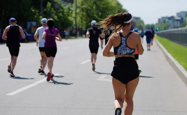 Young woman running race and using smartphone — Stock Photo, Image