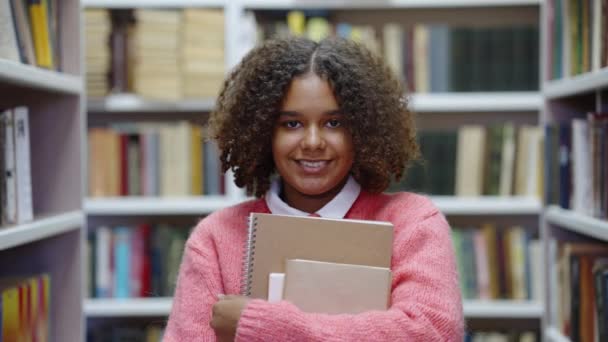 Afrikansk amerikansk flicka ler i biblioteket — Stockvideo