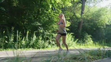 Genç bir kadın yazın dışarıda koşuyor.