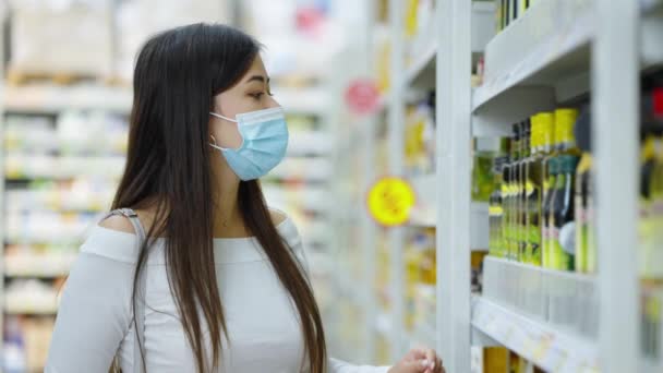 Mujer asiática mirando el aceite de oliva en el supermercado — Vídeos de Stock