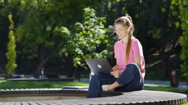 Щаслива жінка проводить відеоконференцію через ноутбук у парку — стокове відео