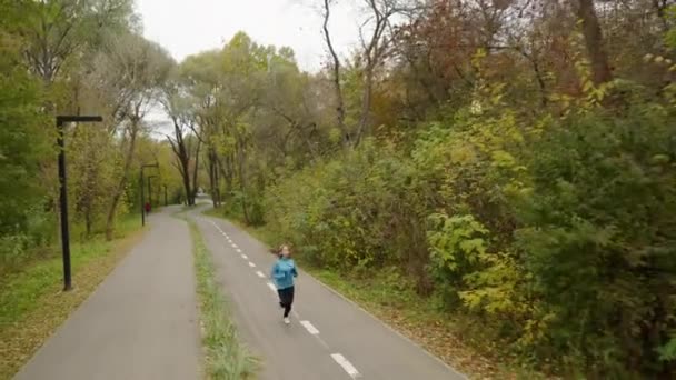 Mujer corriendo en el parque en temporada de otoño — Vídeos de Stock