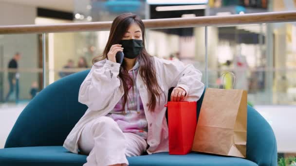 Žena v masce mluví na telefonu v nákupním centru — Stock video