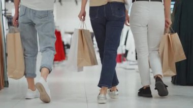 Alışveriş merkezinde alışveriş torbalarıyla dolaşan kadın arkadaşlar.