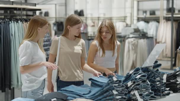 Mutlu kadınlar giyim mağazasından kot pantolon alıyor. — Stok video