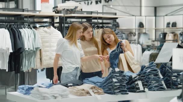 Trzy kobiety kupujące dżinsy w sklepie z ubraniami — Wideo stockowe