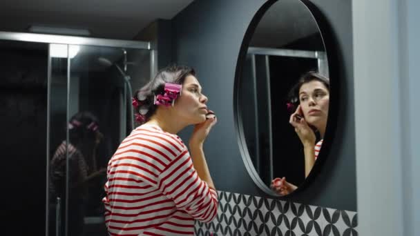 Взрослая женщина наносит румяна делая макияж в ванной комнате — стоковое видео