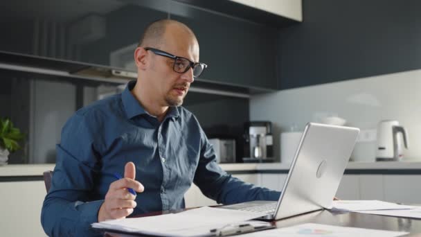 Бизнесмен делает видеозвонок на ноутбуке в домашнем офисе — стоковое видео