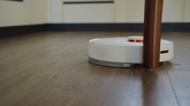 Robot elektrikli süpürge masa bacaklarının etrafında hareket ediyor.