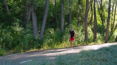 Formda bir adam yazın parkta koşuyor.